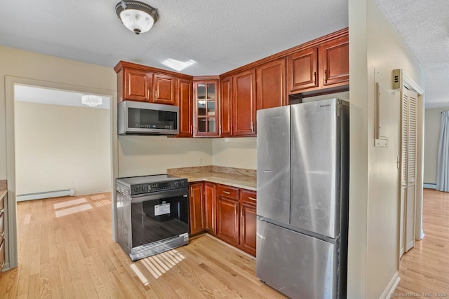 kitchen featuring glass insert cabinets, appliances with stainless steel finishes, light wood-style floors, a textured ceiling, and a baseboard radiator