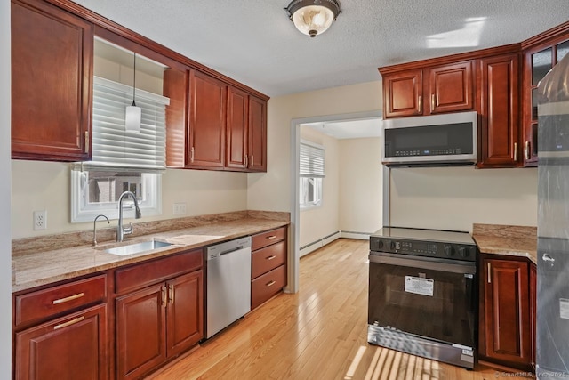 kitchen with light wood-style flooring, a sink, a textured ceiling, appliances with stainless steel finishes, and light stone countertops