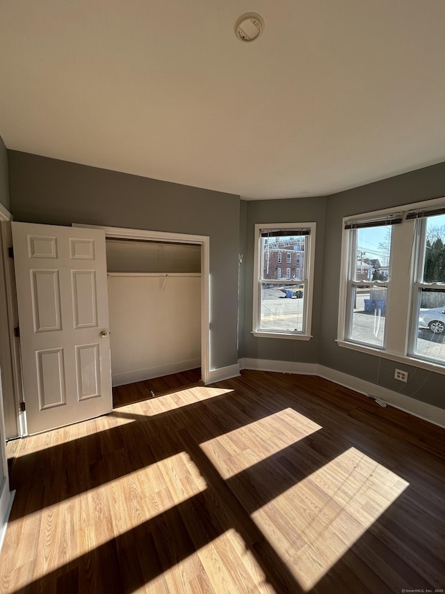 unfurnished bedroom with wood finished floors, a closet, and baseboards