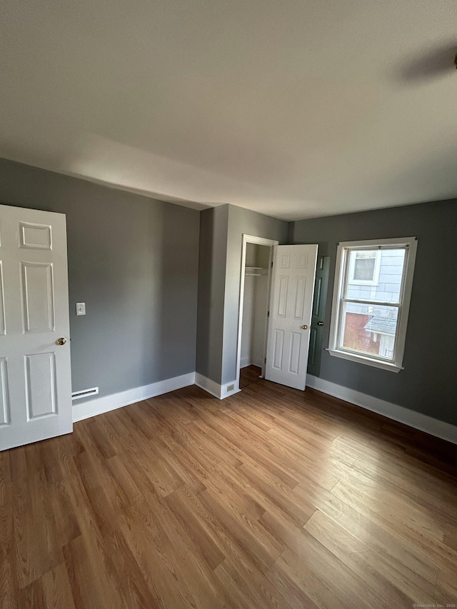 unfurnished bedroom with a closet, baseboards, and wood finished floors