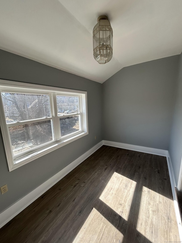 spare room with dark wood finished floors, baseboards, and vaulted ceiling