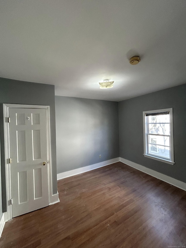 unfurnished room featuring baseboards and dark wood-style floors