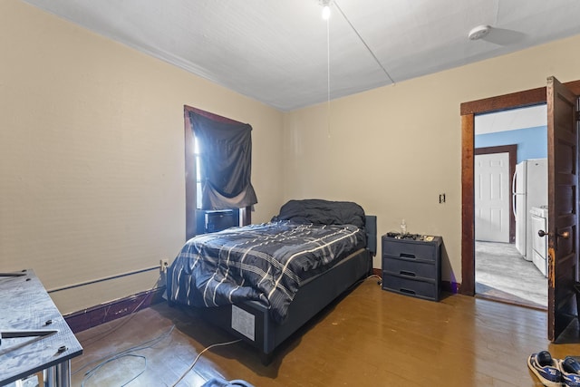 bedroom with freestanding refrigerator, baseboards, and wood finished floors