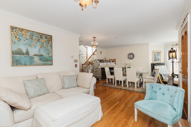 living room with stairway, an inviting chandelier, ornamental molding, light wood-type flooring, and a wealth of natural light