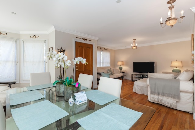 dining room with a chandelier, crown molding, and wood finished floors
