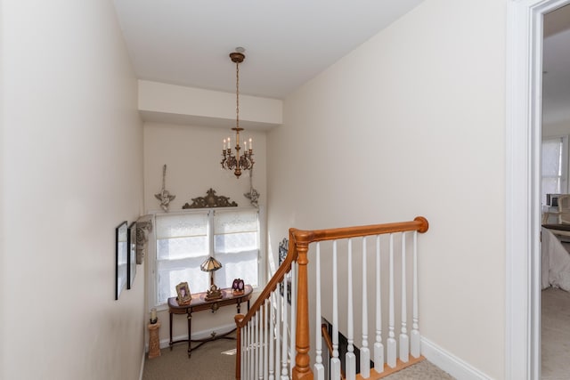 stairs with carpet flooring, baseboards, and a notable chandelier