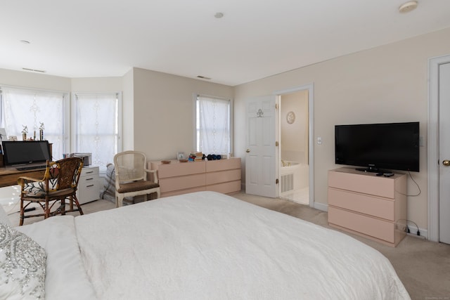 bedroom featuring baseboards, light colored carpet, ensuite bath, and visible vents