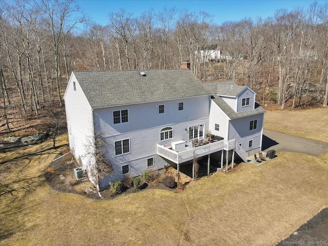 back of house featuring a deck, a yard, a chimney, and a shingled roof