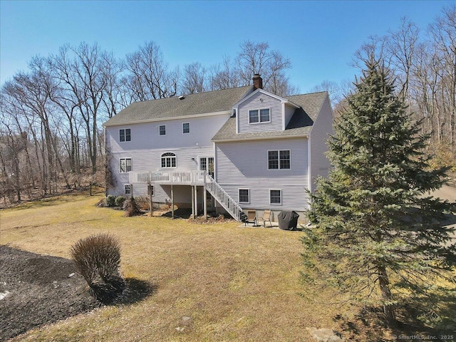 rear view of house with stairway, a chimney, a yard, and a deck