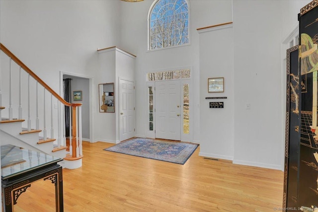 entrance foyer featuring stairway, baseboards, a high ceiling, and wood finished floors