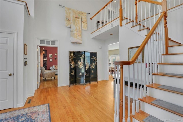 stairs with visible vents, a high ceiling, wood finished floors, and baseboards