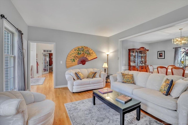 living room with visible vents, baseboards, a notable chandelier, and light wood-style flooring