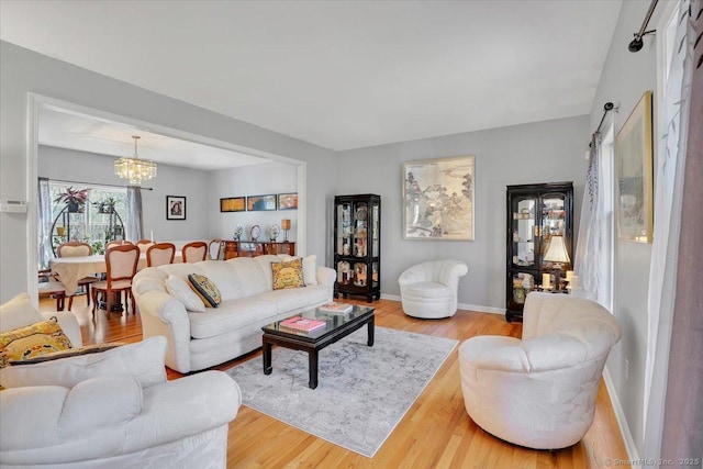 living room featuring a notable chandelier, wood finished floors, and baseboards