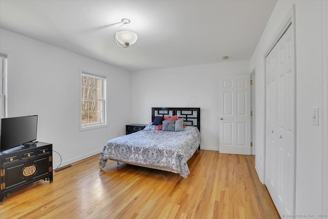 bedroom with a closet, baseboards, and light wood-style floors