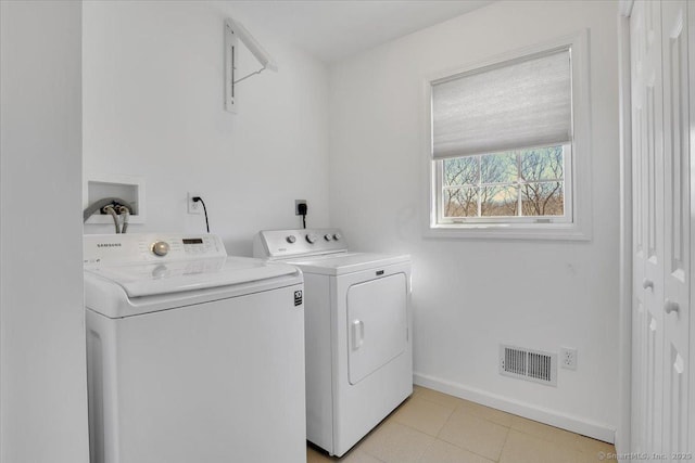 laundry room with visible vents, separate washer and dryer, light tile patterned flooring, baseboards, and laundry area