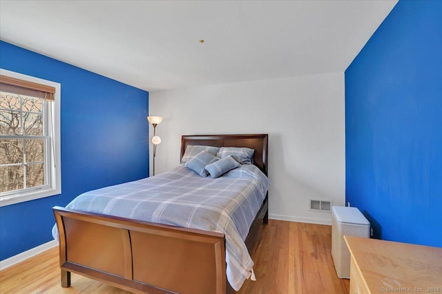 bedroom featuring wood finished floors, visible vents, and baseboards