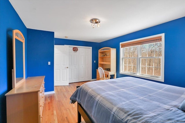 bedroom featuring a closet, light wood-type flooring, and baseboards