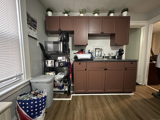 kitchen with a sink, dark countertops, dark wood-style floors, and a textured ceiling