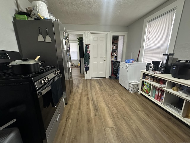 kitchen with wood finished floors, gas range oven, and a textured ceiling