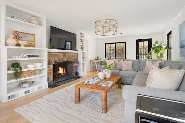 living area with built in features, a stone fireplace, wood finished floors, and ornamental molding