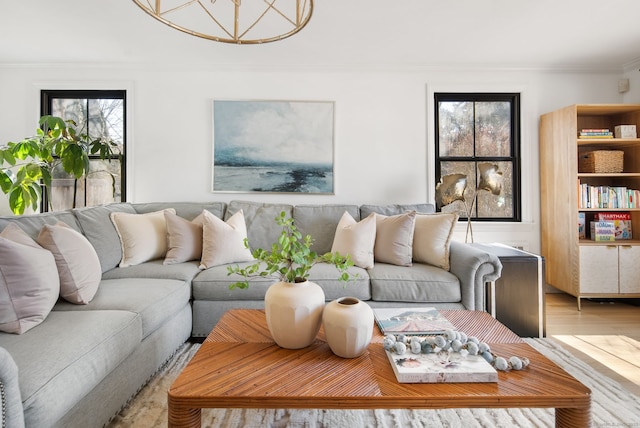 living area featuring a healthy amount of sunlight, light wood-type flooring, and ornamental molding