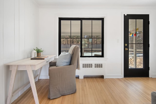 interior space featuring hardwood / wood-style flooring, radiator heating unit, crown molding, and baseboards