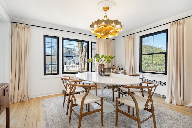 dining space with light wood finished floors, a chandelier, radiator heating unit, and crown molding