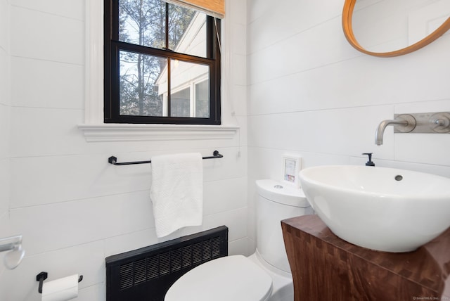 half bath featuring a sink, toilet, and tile walls