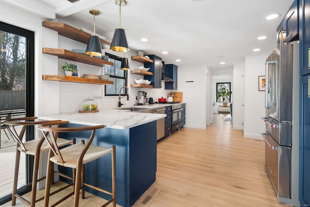 kitchen featuring open shelves, blue cabinetry, plenty of natural light, and stainless steel appliances