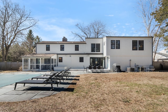 rear view of property with a shingled roof, fence, a chimney, a sunroom, and a patio area