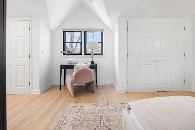 bedroom featuring light wood-type flooring, baseboards, and vaulted ceiling