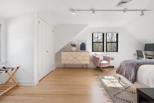 bedroom featuring radiator, baseboards, visible vents, light wood finished floors, and lofted ceiling