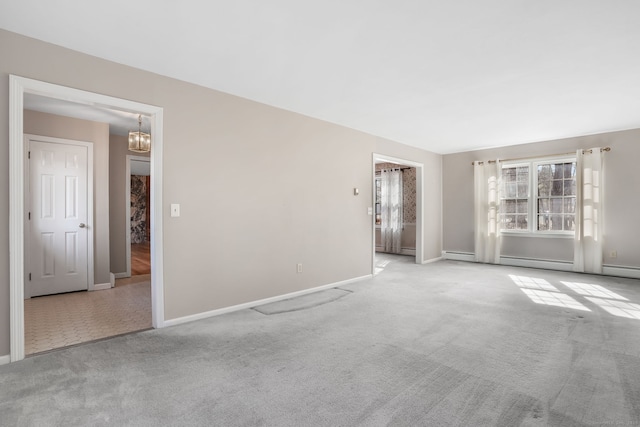 carpeted spare room featuring a baseboard heating unit, baseboards, and a chandelier