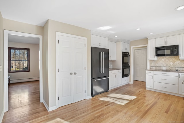 kitchen with light wood finished floors, white cabinetry, decorative backsplash, black appliances, and a baseboard heating unit