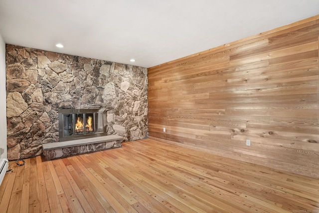 unfurnished living room featuring recessed lighting, a fireplace, wood walls, and wood-type flooring