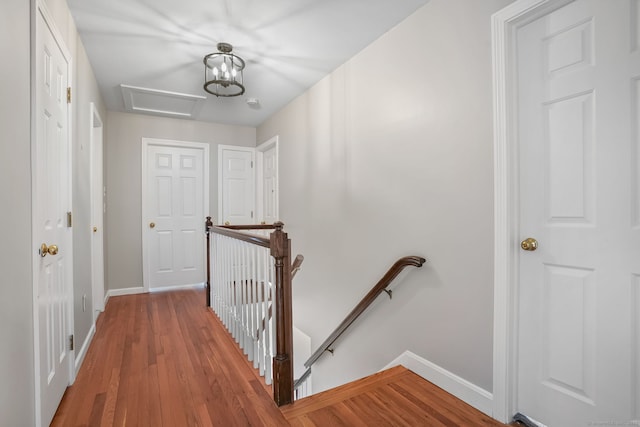 hall featuring baseboards, light wood-type flooring, an upstairs landing, and attic access