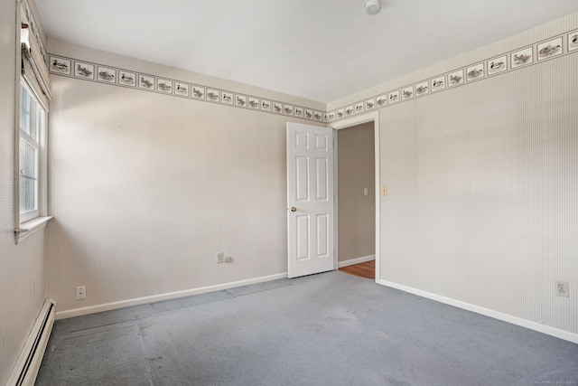 spare room featuring baseboards, a baseboard heating unit, and carpet