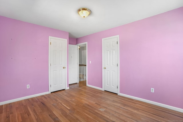 unfurnished bedroom with wood finished floors and baseboards