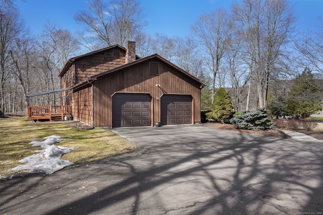 view of side of property with a garage, a chimney, and driveway