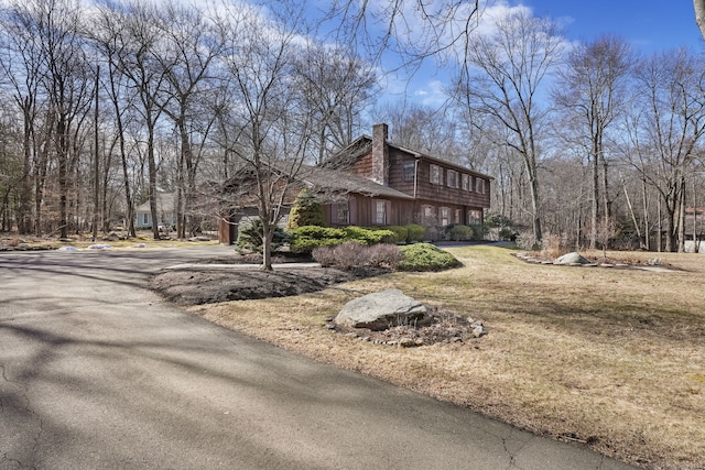 view of home's exterior featuring aphalt driveway and a chimney