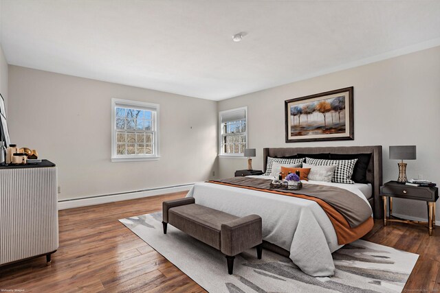 bedroom with a baseboard heating unit and wood-type flooring