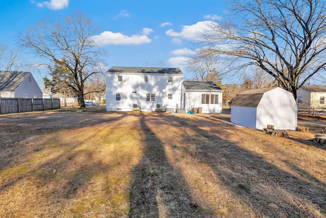 rear view of property featuring an outbuilding, a shed, and fence