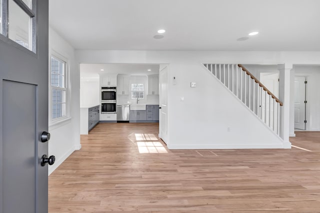 foyer entrance with recessed lighting, light wood-type flooring, a wealth of natural light, and stairway