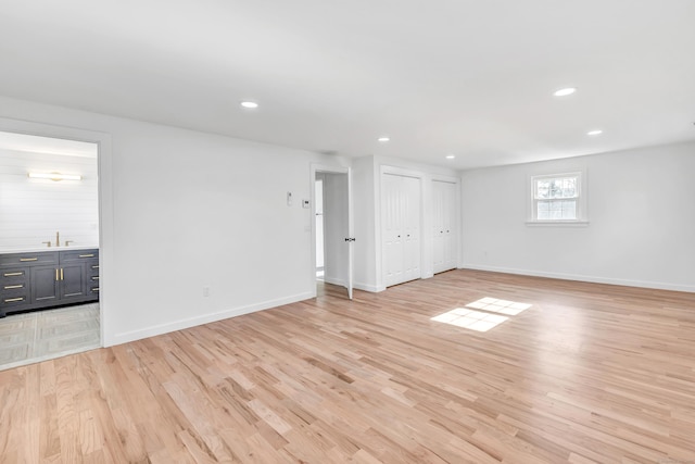 spare room with a sink, light wood-type flooring, baseboards, and recessed lighting