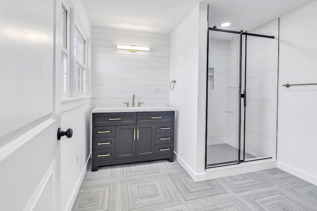 bathroom with baseboards, a stall shower, vanity, and wood walls