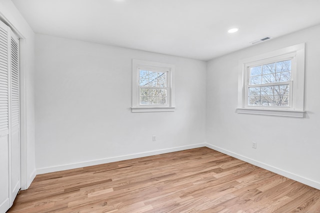 unfurnished bedroom with light wood finished floors, visible vents, baseboards, recessed lighting, and a closet