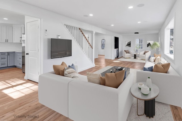 living room with recessed lighting, light wood-style flooring, and stairs