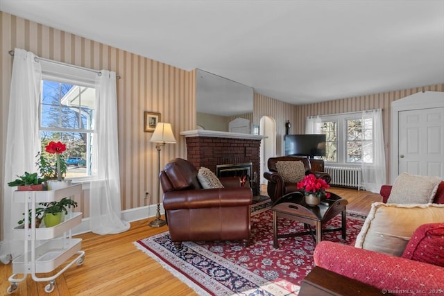 living area featuring wallpapered walls, radiator heating unit, baseboards, and wood finished floors