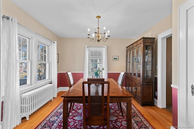 dining room with a notable chandelier, radiator heating unit, light wood-style floors, and baseboards