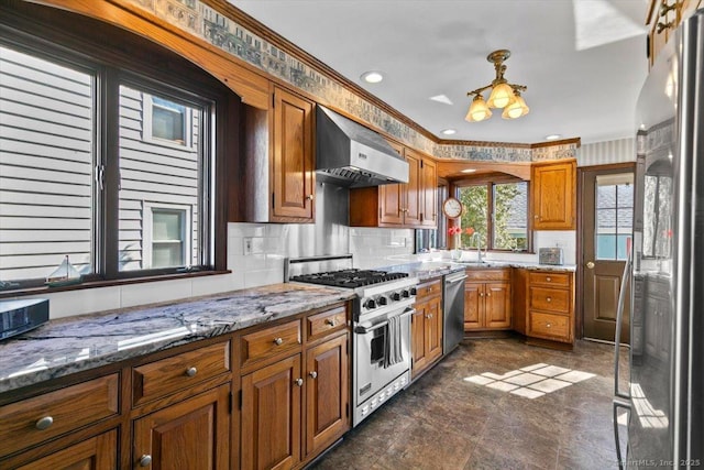 kitchen with light stone counters, brown cabinets, ventilation hood, and stainless steel appliances